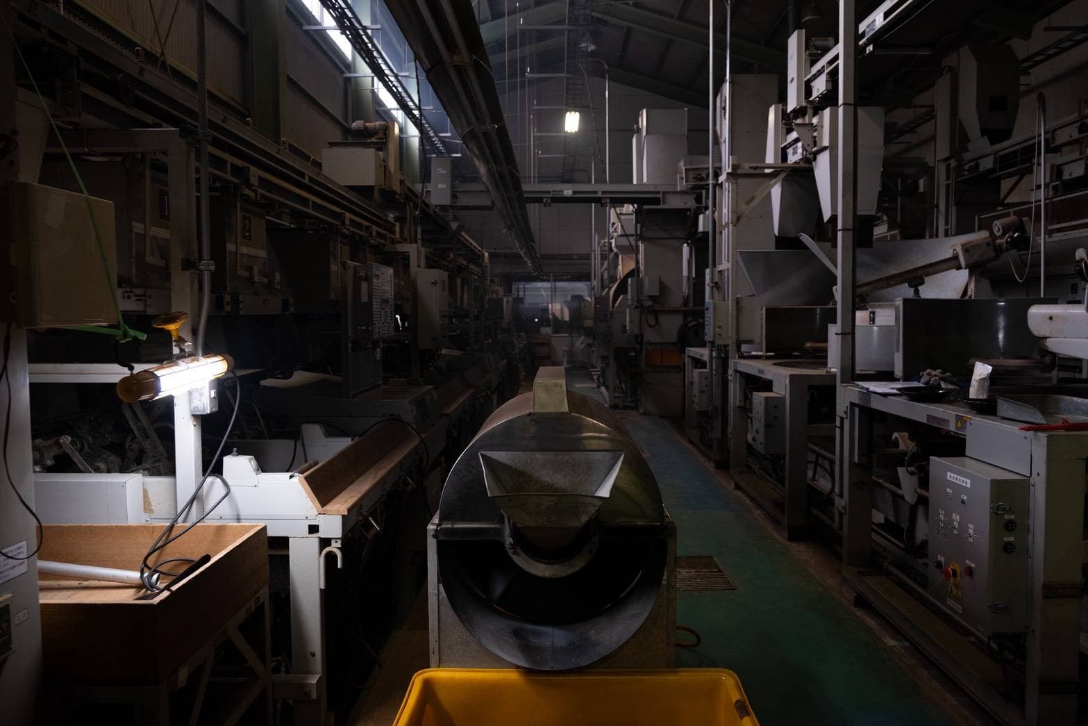 薄暗い製茶工場の通路に、長く連なる選別機・乾燥機
